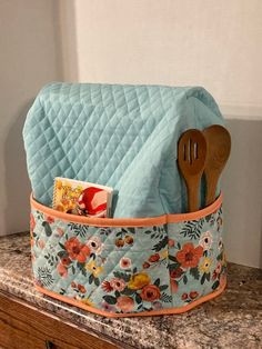 a blue quilted pot holder with utensils in it