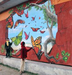 two people are standing in front of a painted mural on the side of a building