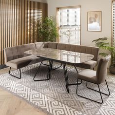 a dining table with four chairs and a bench in front of it on top of a rug