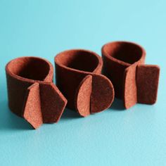 four pieces of brown felt sitting next to each other on a blue surface with one piece cut out