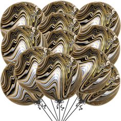 a bunch of balloons that are shaped like marbles and have black, white, and gold swirls on them