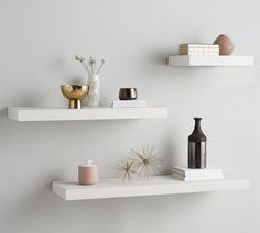 two white shelves with vases and other items on them