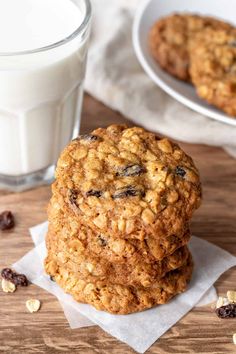 three oatmeal cookies sitting on top of each other next to a glass of milk