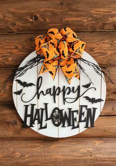 a sign that says happy halloween with bats and spider webs on it, hanging on a wooden wall