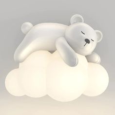 a white teddy bear laying on top of a cloud shaped light fixture with its eyes closed