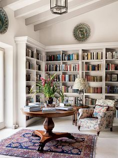 a living room filled with lots of books on top of a book shelf next to a table