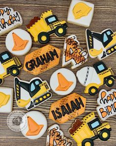 decorated cookies with construction vehicles and name written on them are laid out on a wooden surface