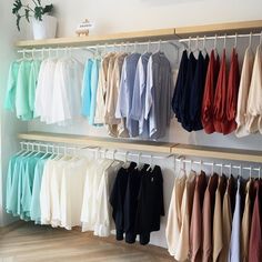 there are many shirts hanging on the rack in this room, all different colors and sizes