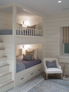 a room with two bunk beds and a chair next to it on a rug in front of the stairs