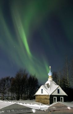 an image of the aurora bore in the sky over a church and snow covered ground