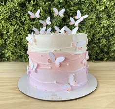 there is a three layer cake with butterflies on the top and pink frosting around the edges