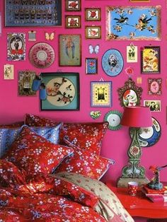 a bedroom with pink walls and lots of pictures on the wall above the headboard