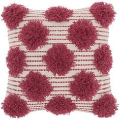 a red and white pillow with pom - poms on it