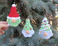 three crocheted christmas ornaments hanging from a pine tree in front of someone's hand