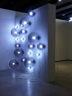 an art installation with lights on the wall and balls hanging from it's sides