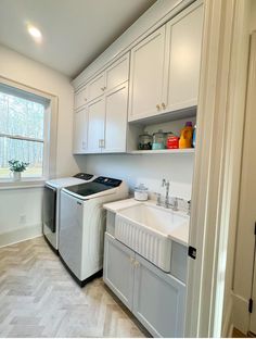 a washer and dryer in a small room with white cabinets on the walls