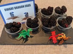 several plastic cups filled with blackberries on top of a table next to a sign