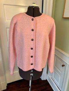 a pink cardigan sweater on a mannequin in front of a white door