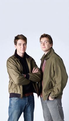 two men standing next to each other in front of a white background with their arms crossed