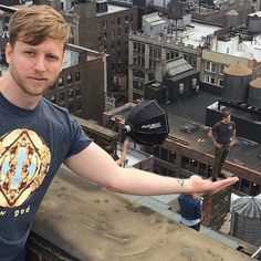 a man standing on top of a tall building holding out his hand to the camera