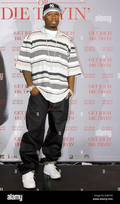 a man standing in front of a red carpet wearing black and white striped shirt, jeans and