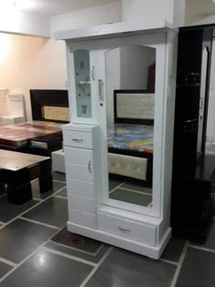 a white cabinet sitting in the middle of a room filled with tables and chairs next to each other