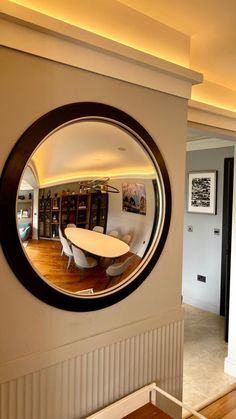 a circular mirror is hanging on the wall in front of a dining room table and bookshelf