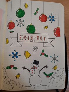 an open notebook with christmas decorations and a snowman on the page, which reads december