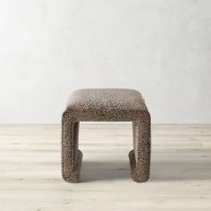 an animal print stool sits in front of a white wall and wooden floor with no one on it