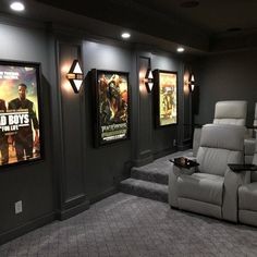 an empty movie theater with two recliners and three movie posters on the wall