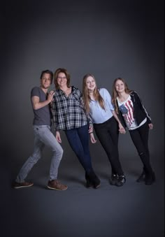 four people posing for a photo in front of a dark background