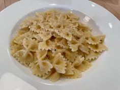 a white bowl filled with pasta on top of a wooden table