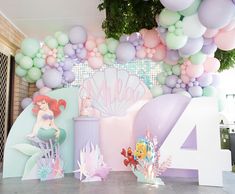 there are balloons and decorations on the wall at this birthday party with little mermaids