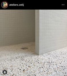 a bathroom with white tiles and black dots on the floor is seen in this image