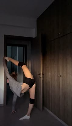 a woman doing a handstand on the floor in front of a closet door