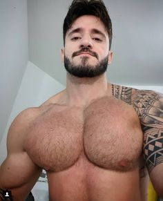 a shirtless man with tattoos on his chest and arms is taking a selfie