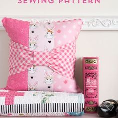 a pink pillow sitting on top of a bed next to a pair of black shoes