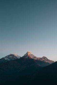 the mountains are covered in snow as the sun is low to the ground and there is no cloud