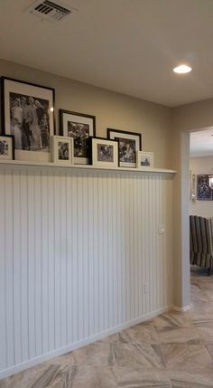 a living room with pictures on the wall and tile flooring in front of it