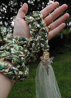 a woman's hand is holding some green and gold bracelets