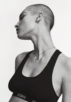 a black and white photo of a woman with shaved hair wearing a sports bra top