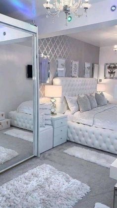 a white bedroom with mirrored walls and chandelier hanging from the ceiling, carpeted floor