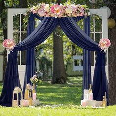 an outdoor wedding ceremony setup with blue drapes and pink flowers on the arch,