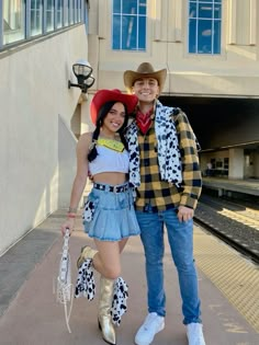 a man and woman in cowboy hats posing for a photo at the train station with their arms around each other