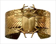 a gold bracelet with a beetle on it's center and wings in the middle