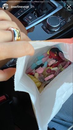 a person is holding a bag full of candy in their hand and there is a car steering wheel behind them