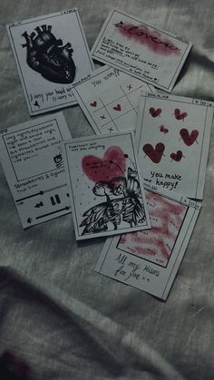 several cards with drawings and hearts on them sitting on a sheet of paper next to each other