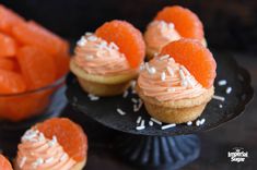 small cupcakes with orange frosting and sprinkles on black plates