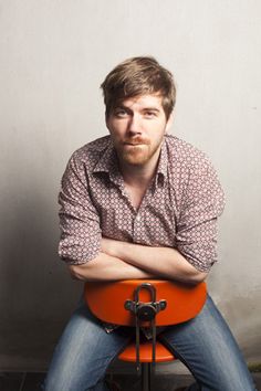 a man sitting on an orange chair with his arms crossed