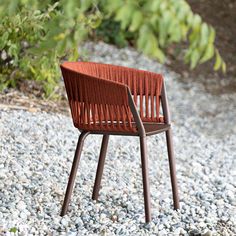 a red chair sitting on top of a gravel covered ground